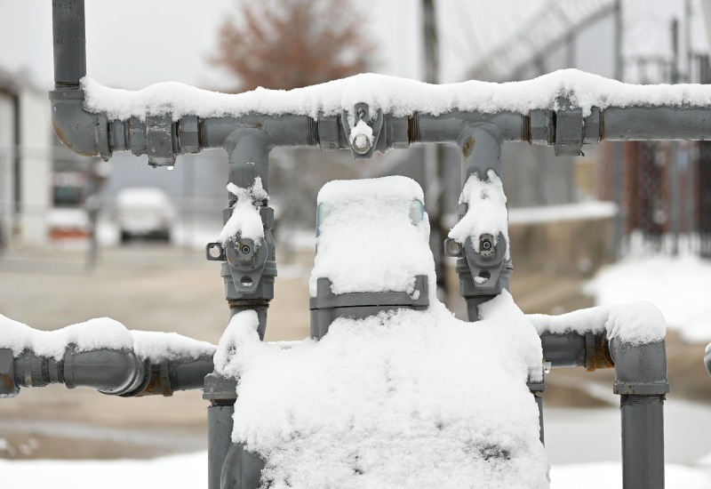 Frozen outdoor water pipes covered in snow during winter in Illinois