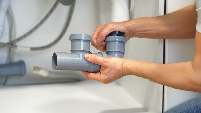 Installing new drain pipe fittings under the sink, plumbing upgrade in Naperville, IL